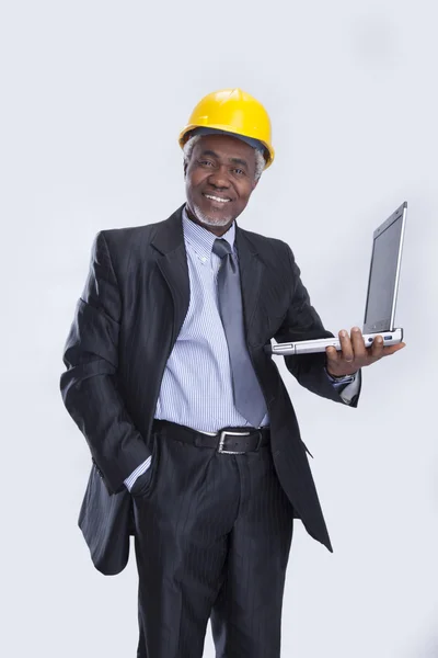 Homem de negócios envelhecido com capacete amarelo e laptop — Fotografia de Stock