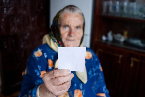 Mulher idosa segurando folha de papel branco para o seu texto — Fotografia de Stock