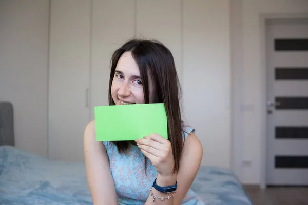 Lächelndes Mädchen hält Blatt grünen Papiers für Ihren Text in der Hand — Stockfoto