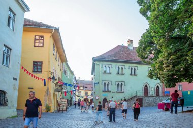 Sighisoara, Romanya - Ağustos 2019: Sighisoara 'nın güzel merkezi ve yaz sokak yaşamı. Bu kasaba Drakula 'nın doğduğu yer. Transilvanya 'nın ortasında bir ortaçağ şehri. Yerel halk ve turistler yürüyor