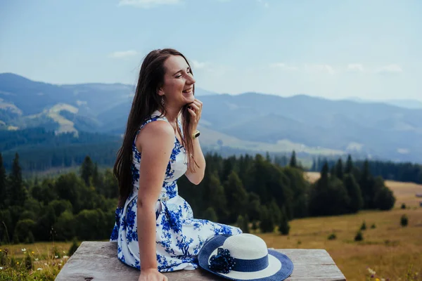 Jovem mulher em vestido elegante descansando no banco nas montanhas — Fotografia de Stock