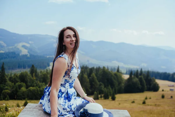 Jovem mulher em vestido elegante descansando no banco nas montanhas — Fotografia de Stock