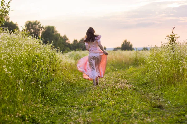 Menina correndo através do campo em um vestido rosa — Fotografia de Stock