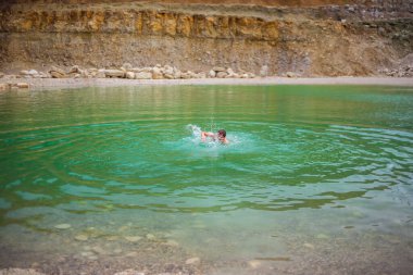 Kanyon gölünde zümrüt renkli berrak suyla yüzen adam.