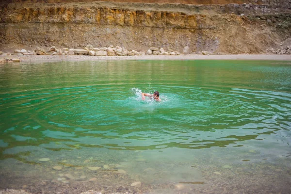 Kanyon gölünde zümrüt renkli berrak suyla yüzen adam.
