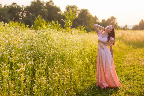 Chica de pie en el campo en un vestido rosa — Foto de Stock