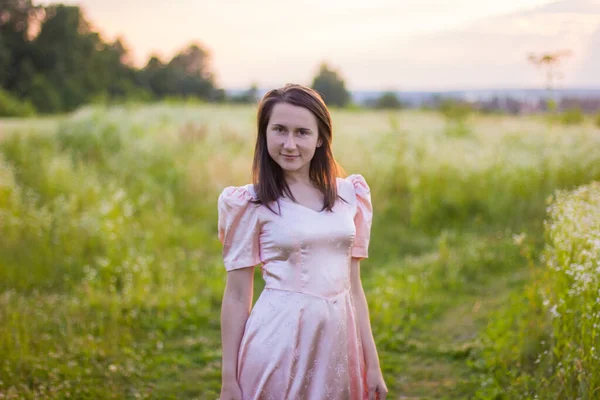 Mädchen steht im rosa Kleid auf dem Feld — Stockfoto