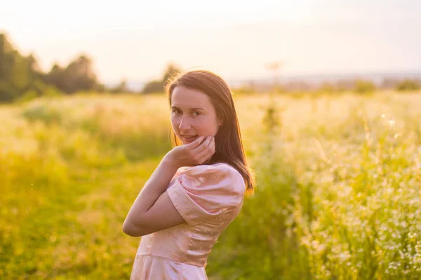 Chica de pie en el campo en un vestido rosa —  Fotos de Stock