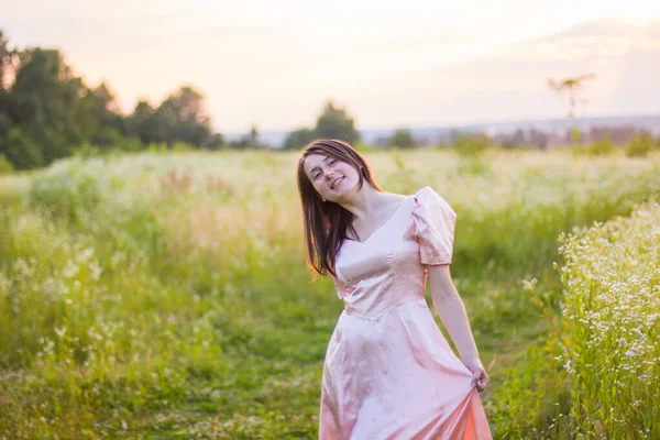 Menina de pé no campo em um vestido rosa — Fotografia de Stock