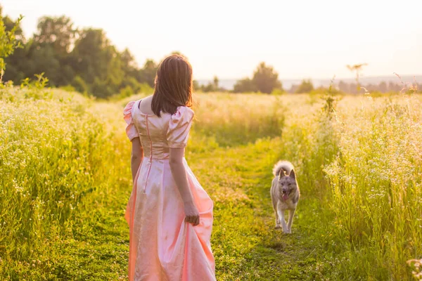 Menina de pé no campo em um vestido rosa — Fotografia de Stock