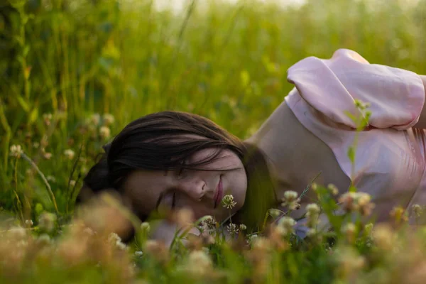 Фото красивой спящей женщины в поле с полевыми цветами — стоковое фото