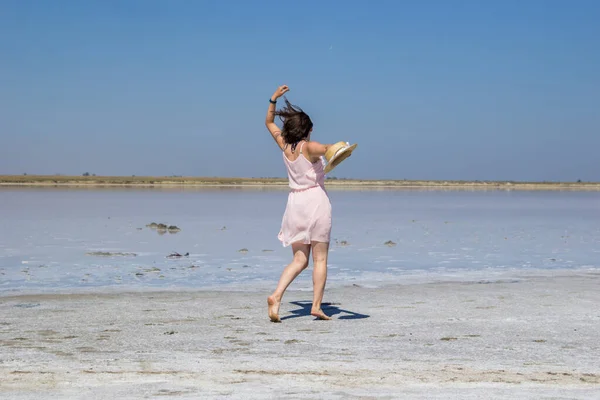 Chica en un vestido corre descalzo a lo largo de las orillas de un lago salado — Foto de Stock