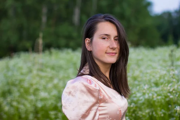 Chica de pie en el campo en un vestido rosa — Foto de Stock