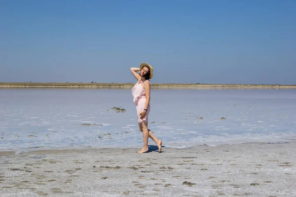 Chica en un vestido que va descalzo a lo largo de las orillas de un lago salado — Foto de Stock