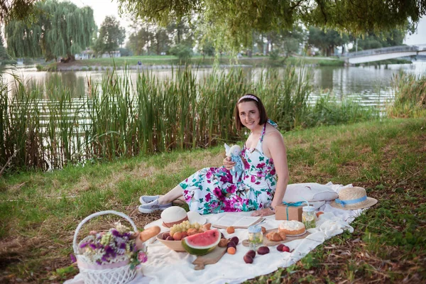 Eine junge Frau sitzt auf einem Picknick in einem Park am Ufer eines Flusses — Stockfoto