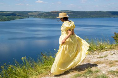 Koyun kenarındaki uçurumda duran uzun elbiseli bir kız.