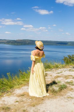 Koyun kenarındaki uçurumda duran uzun elbiseli bir kız.