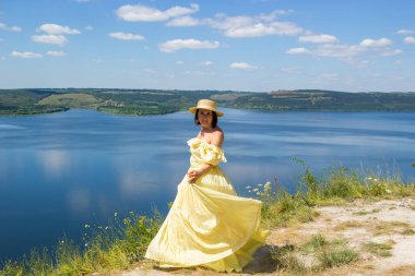 Koyun kenarındaki bir uçurumda dans eden uzun elbiseli bir kız.