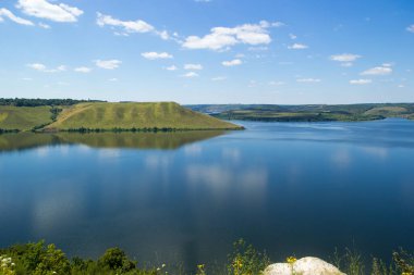 Güneşli bir günde tepeler arasında büyük bir gölün güzel panoramik manzarası
