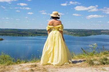 Koyun kenarındaki uçurumda duran uzun elbiseli bir kız.