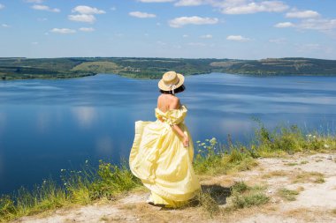 Koyun kenarındaki bir uçurumda dans eden uzun elbiseli bir kız.