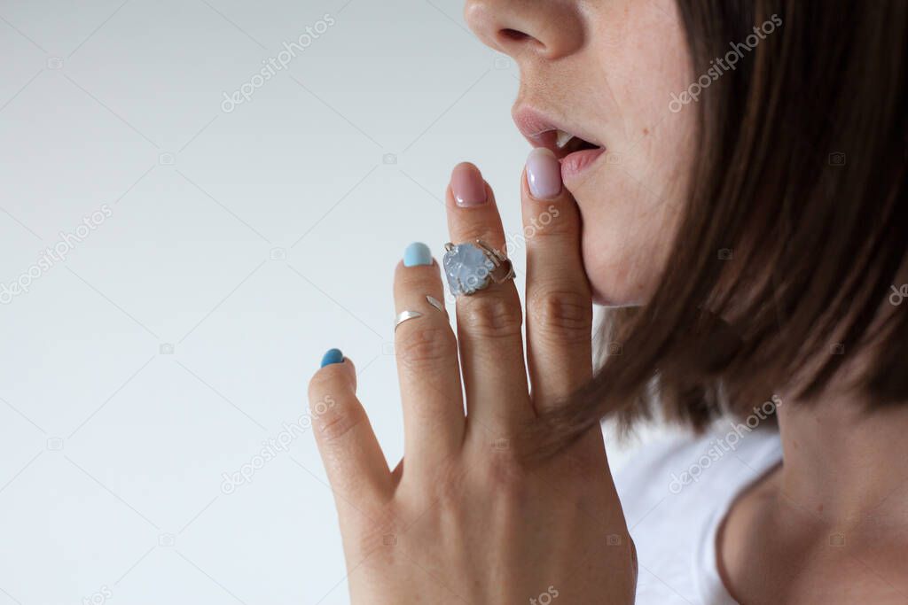 Side view of a female touching her lips with her fingers with two rings