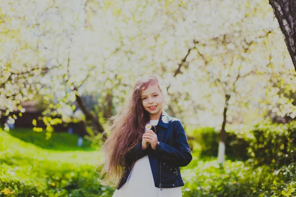 Menina em jaqueta preta de pé no jardim de cereja primavera — Fotografia de Stock