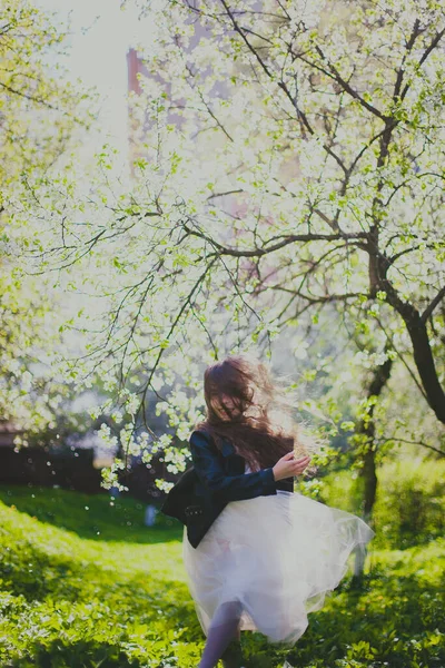 Niña en chaqueta negra y vestido blanco bailando en el jardín de cerezos de primavera —  Fotos de Stock