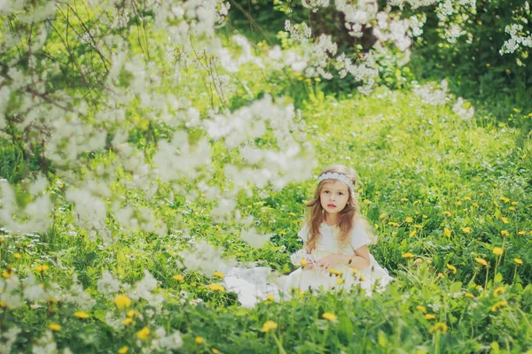 Mädchen im Kleid sitzt im Frühling Kirschgarten — Stockfoto