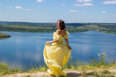 Koyun kenarındaki bir uçurumda dans eden uzun elbiseli bir kız.