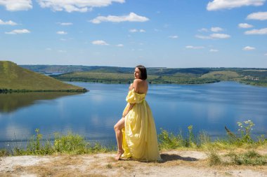 Koyun kenarındaki uçurumda duran uzun elbiseli bir kız.