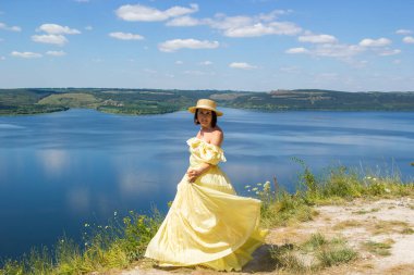 Koyun kenarındaki bir uçurumda dans eden uzun elbiseli bir kız.