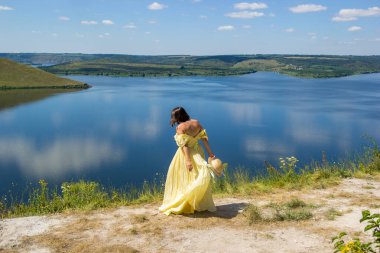 Koyun kenarındaki bir uçurumda dans eden uzun elbiseli bir kız.