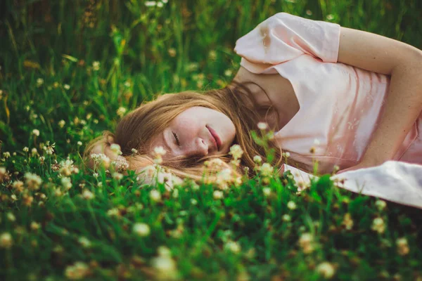 Zdjęcie pięknej śpiącej kobiety w fild z dzikimi kwiatami — Zdjęcie stockowe