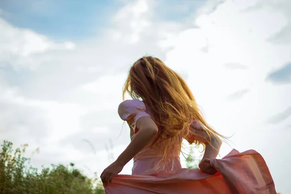 Chica corriendo a través del campo en un vestido rosa —  Fotos de Stock