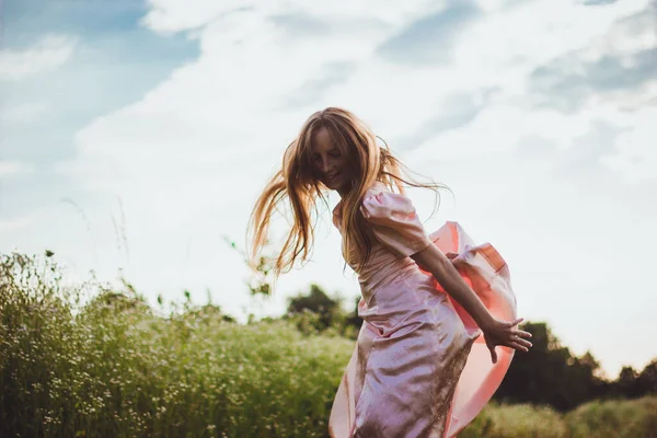 Девушка прыгает в поле в розовом платье — стоковое фото