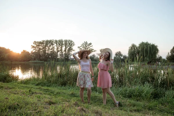 Dwie dziewczyny stojące nad jeziorem o zachodzie słońca — Zdjęcie stockowe