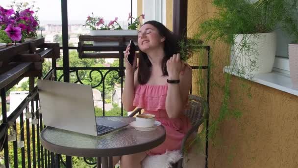 Γυναίκα που χρησιμοποιεί φορητό υπολογιστή και smartphone στο μπαλκόνι — Αρχείο Βίντεο