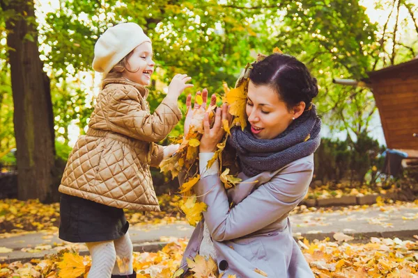 Молодая мать и ее дочь веселятся осенью — стоковое фото