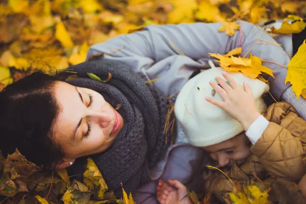 Молодая мать и ее дочь веселятся осенью — стоковое фото