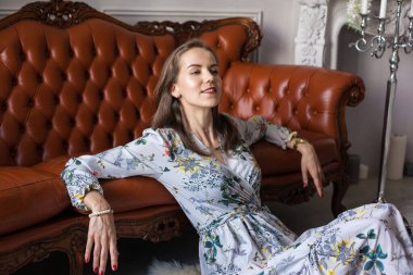 Çiçekli elbiseli genç bir kadın yerde oturuyor.