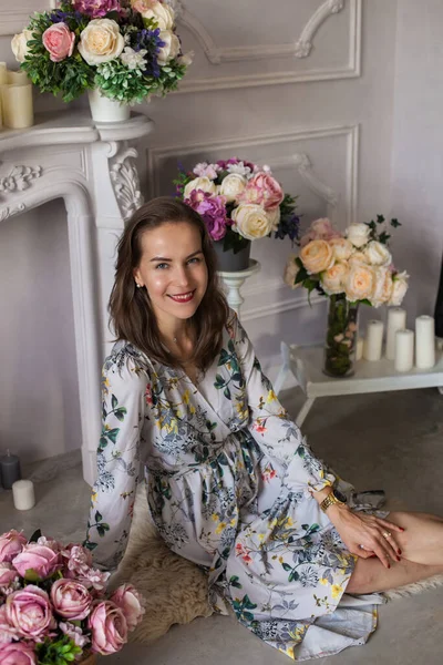 Schöne junge Frau sitzt in einem Raum zwischen den Blumen — Stockfoto
