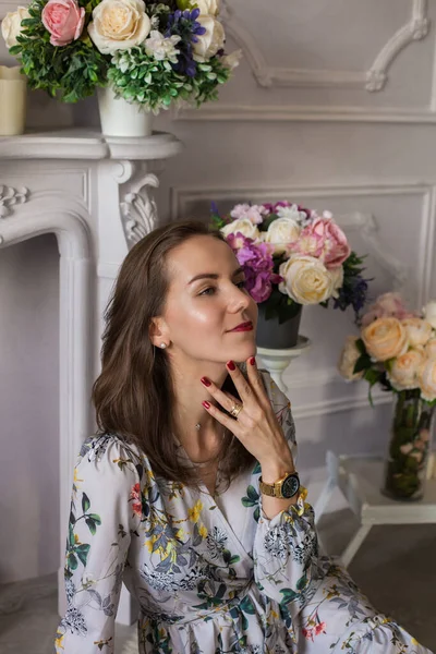 Schöne junge Frau sitzt in einem Raum zwischen den Blumen — Stockfoto
