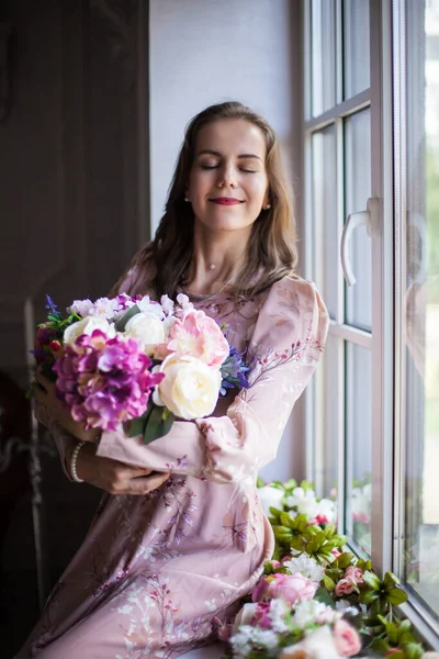 Frau mit braunen Haaren und roten Lippen, bekleidet mit einem rosa Kleid — Stockfoto