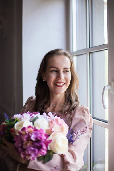 Frau mit braunen Haaren und roten Lippen, bekleidet mit einem rosa Kleid — Stockfoto