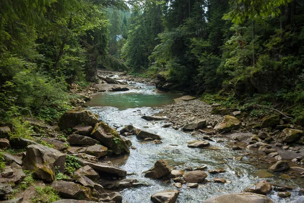 Маленькая река течет быстро и ярко по своей дикой каменистой долине — стоковое фото