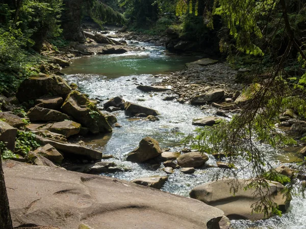 Маленькая река течет быстро и ярко по своей дикой каменистой долине — стоковое фото