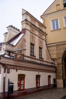 Lublin, Polonya, 25 Kasım 2025: Eski bir bina soğuk bir kış günü duvarlarında ayrıntılı sanat eserlerini gösteriyor. Şehirdeki çatıların bir kısmı karla kaplı..