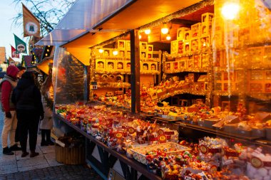 Gdansk, Polonya, 27 Kasım 2025: Mallarla dolu tezgahlar cadde boyunca oturur. Noel piyasa sahnesi. İnsanlar akşam saatlerinde tatlı ikram ve süslemelerle dolu festival pazarına göz atıyorlar.