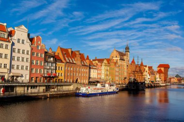 Gdansk, Polonya, 27 Kasım 2025: Gdansk 'ta nehir kıyısındaki parlak binalar. Tekneler mavi bir gökyüzünün altında suda yüzerler. Gündüz oldu ve bölge hareketli..